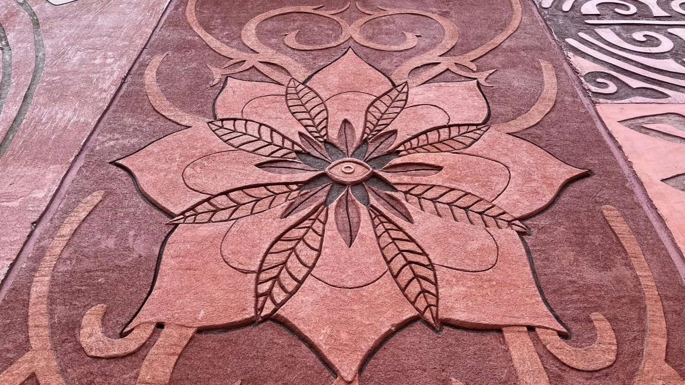 Esgrafiado en relieve con forma de flor sobre un muro rosa